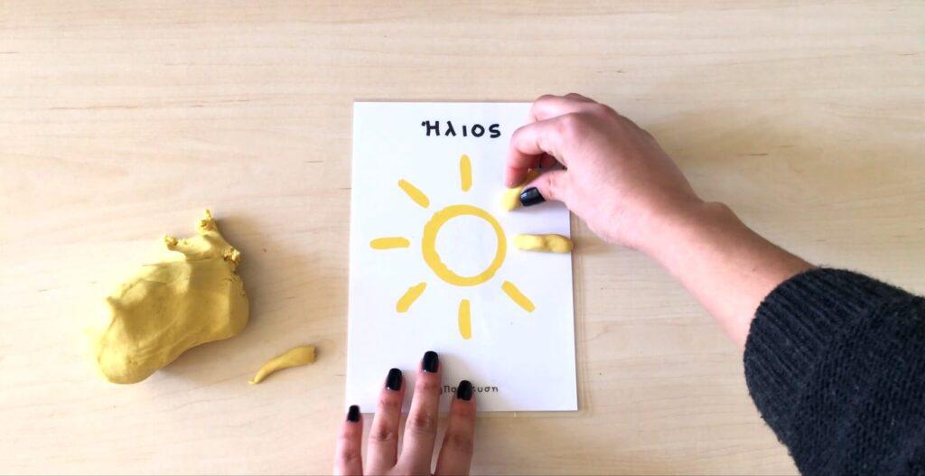 Η εικόνα απεικονίζει κάποιον να σχεδιάζει έναν ήλιο με πλαστελίνη