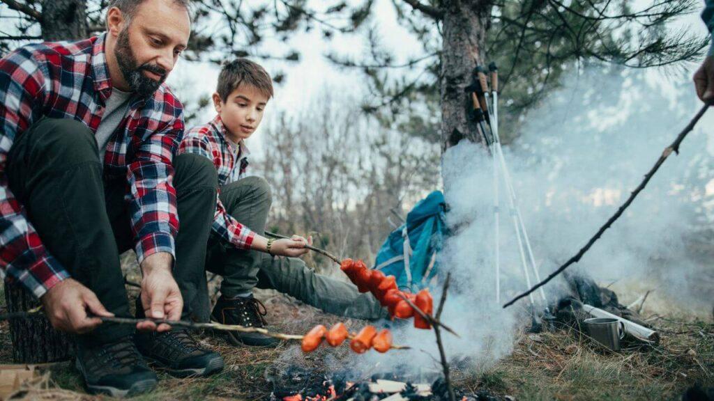 Η εικόνα απεικονίζει ένα μπαμπά που κάνει camping μαζί με το γιο του