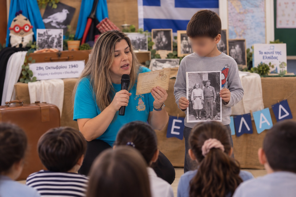 Εμψυχώτρια παρουσιάζει στα παιδιά ένα παλιό γράμμα και φωτογραφία στο εκπαιδευτικό πρόγραμμα της EggΠαίδευσης για την 28η Οκτωβρίου