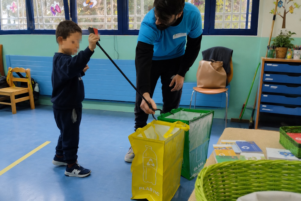 Παιδί συμμετέχει σε βιωματικό παιχνίδι ανακύκλωσης και ταξινομεί υλικά στους σωστούς κάδους